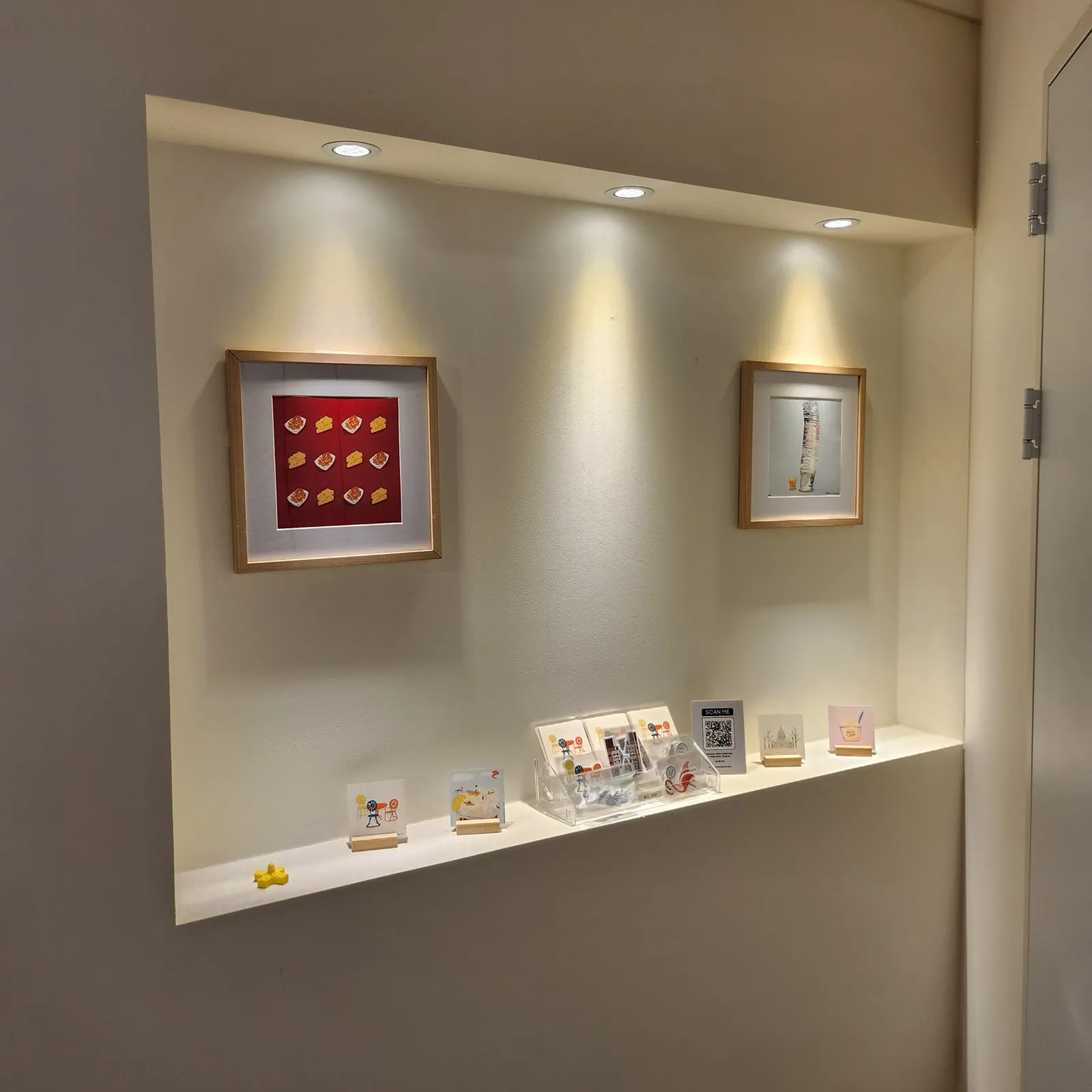 Framed work and cards in a lit display niche